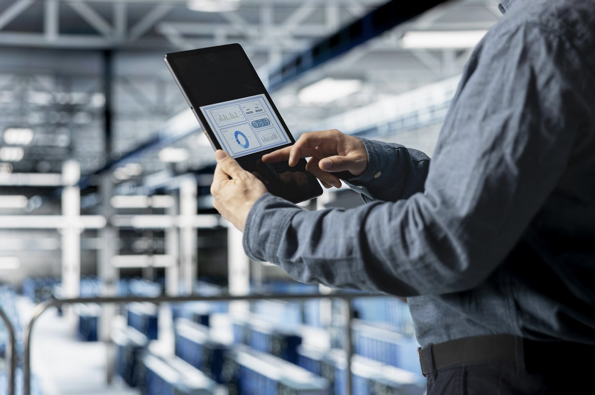 Technician using tablet to monitor maintenance data in industrial facility